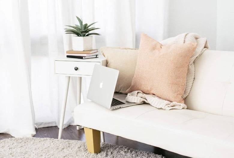 Laptop on a beige sofa with a pillow and throw - how to update old blog posts. 
